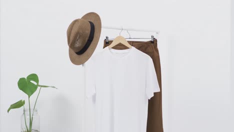Video-of-white-t-shirt-on-hanger-with-hat-and-skirt-and-copy-space-on-white-background