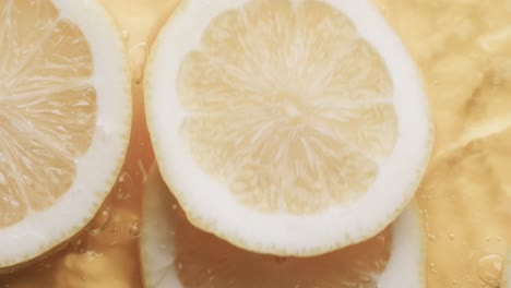 Video-of-slices-of-lemon-falling-into-water-with-copy-space-on-yellow-background