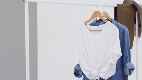 Video-of-white-and-denim-t-shirt-on-hangers,-hat-and-copy-space-on-white-background