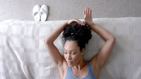 Biracial-woman-taking-nap-on-bed-in-bedroom,-slow-motion