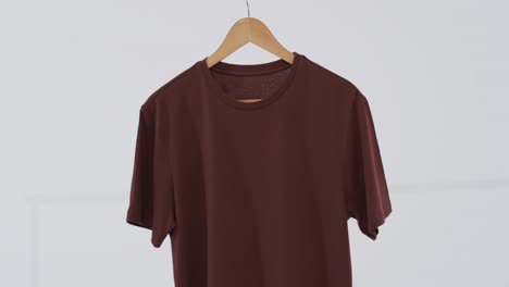 Video-of-brown-t-shirt-on-hanger-and-copy-space-on-white-background