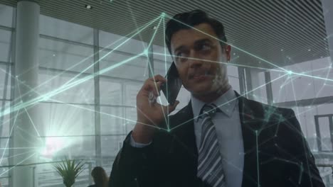 Animation-of-network-of-connections-against-caucasian-businessman-talking-on-smartphone-at-office