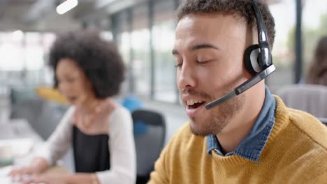 Portrait-of-biracial-man-talking-on-phone-headset-at-office
