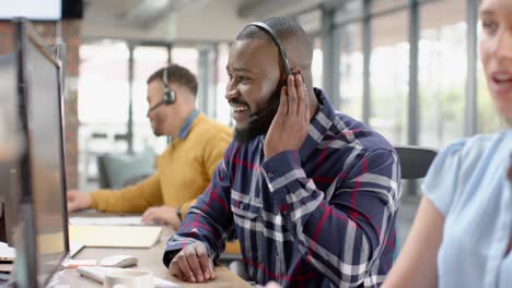 Portrait-of-happy-african-american-businessman-talking-on-phone-headset-at-office