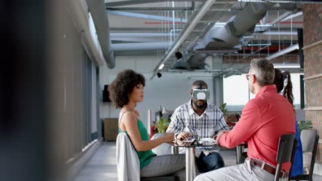 African-american-businessman-wearing-vr-headset-while-colleagues-watching-him-at-office