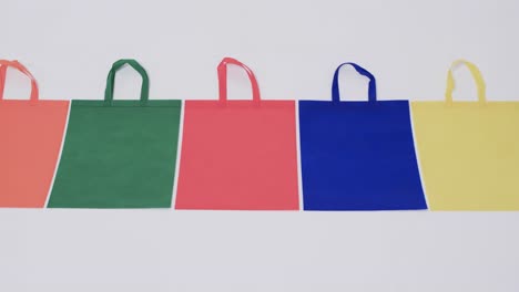 Video-of-row-of-multi-coloured-canvas-bags-with-copy-space-on-white-background