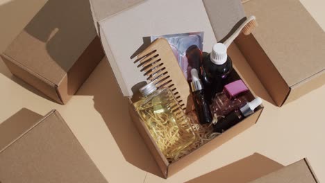 Vertical-video-of-beauty-products-in-cardboard-box-with-boxes-and-copy-space-over-brown-background