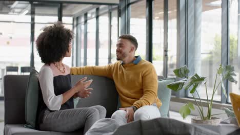 Diverse-man-and-woman-discussing-with-each-other-sitting-on-the-couch-at-office