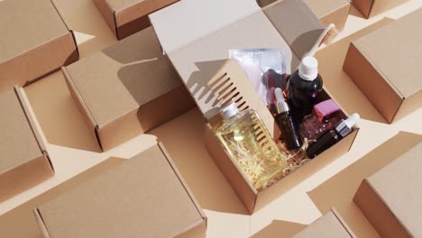 Vertical-video-of-beauty-products-in-cardboard-box-with-boxes-and-copy-space-over-brown-background