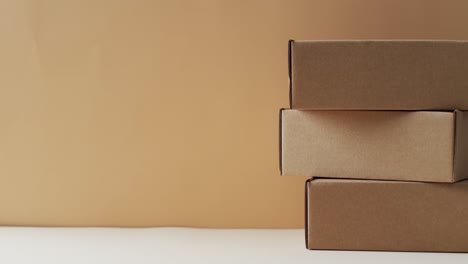 Video-of-stacked-cardboard-boxes-with-copy-space-over-brown-background