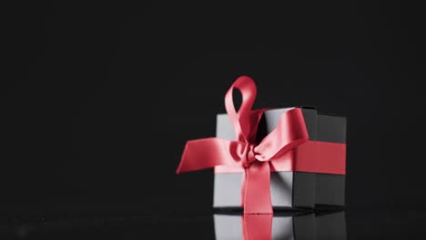 Video-of-gift-box-with-red-ribbon-and-copy-space-over-black-background