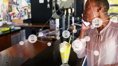 Animation-of-connected-dots-over-african-american-woman-picking-up-cellphone-while-drinking-juice