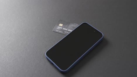 Video-of-smartphone-with-blank-screen,-boxes-and-credit-card-with-copy-space-on-grey-background