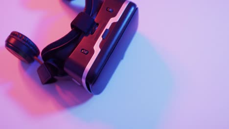 Video-of-close-up-of-video-game-pad-vr-headset-with-copy-space-on-neon-background
