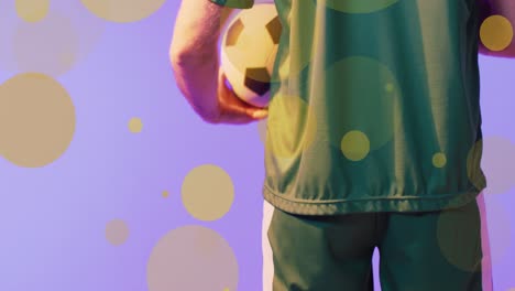Animation-of-lens-flares-over-midsection-of-caucasian-player-holding-soccer-ball