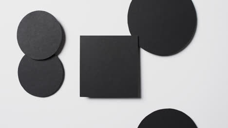 Video-of-close-up-of-square-and-circles-of-black-paper-and-copy-space-on-white-background