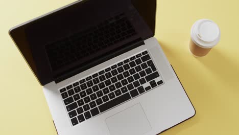 Video-Eines-Laptops-Mit-Leerem-Bildschirm-Und-Kaffeetasse-Auf-Gelbem-Hintergrund