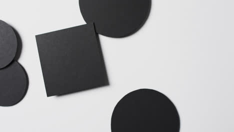 Video-of-close-up-of-square-and-circles-of-black-paper-and-copy-space-on-white-background