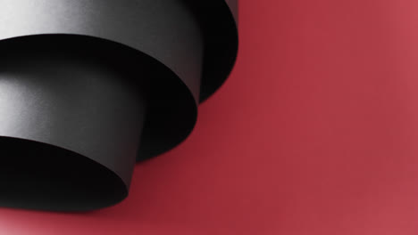 Close-up-of-rolls-of-black-paper-and-copy-space-on-red-background
