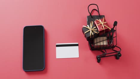 Video-Eines-Smartphones-Mit-Leerem-Bildschirm,-Kreditkarte,-Einkaufswagen-Auf-Rotem-Hintergrund