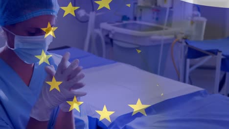 Animation-of-flag-of-europe-over-tired-and-sad-caucasian-female-doctor-joining-hands-in-hospital