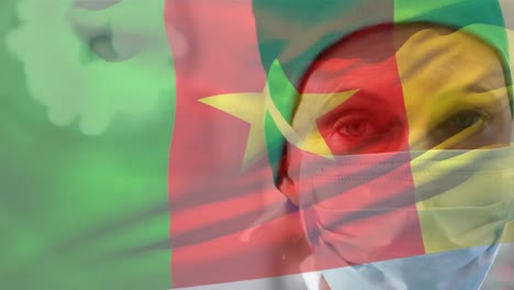 Animation-of-flag-of-cameroon-over-close-up-of-caucasian-doctor-wearing-mask-standing-in-hospital
