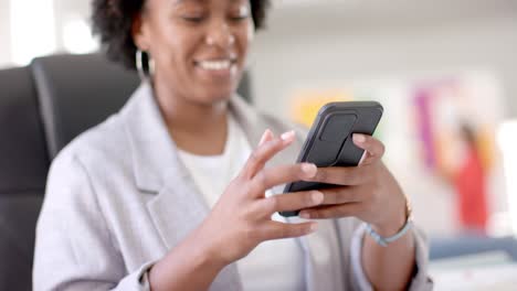 Happy-african-american-casual-businesswoman-using-smartphone-in-office,-slow-motion