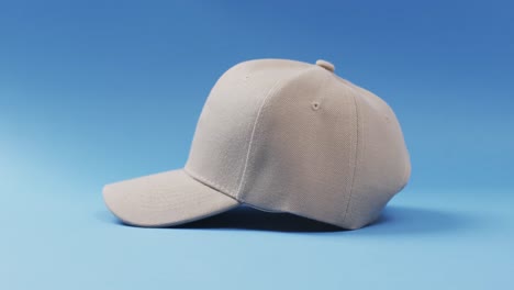 Video-of-beige-baseball-cap-and-copy-space-on-blue-background