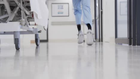 Lowsection-of-african-american-male-doctor-running-in-hospital-corridor,-slow-motion
