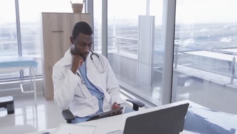 African-american-male-doctor-using-tablet-in-hospital-office,-slow-motion