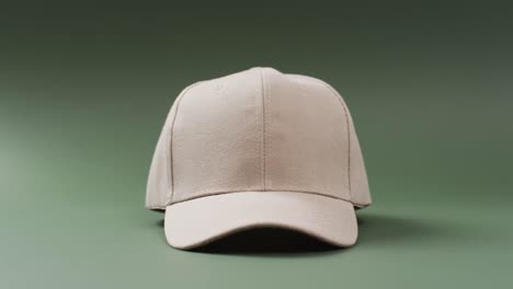Video-of-beige-baseball-cap-and-copy-space-on-green-background