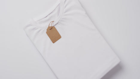 Video-Eines-Weißen-Gefalteten-T-Shirts-Mit-Etikett-Und-Kopierraum-Auf-Weißem-Hintergrund