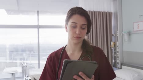 Portrait-of-happy-caucasian-female-doctor-using-tablet-in-hospital-room,-slow-motion