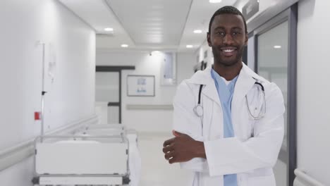 Portrait-of-happy-african-american-male-doctor-in-hospital-corridor-with-copy-space,-slow-motion