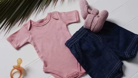 Video-of-pink-baby-grow,-shorts,-dummy-and-pink-booties-with-copy-space-on-white-background