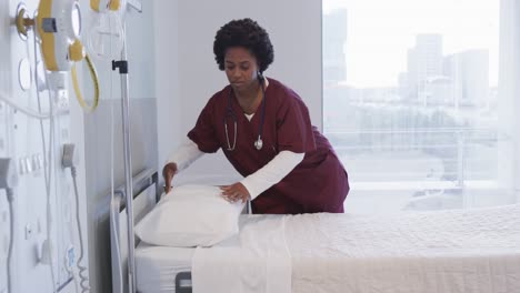 African-american-female-doctor-preparing-bed-in-hospital-room,-slow-motion