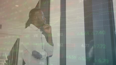 Animation-of-multicolored-trading-board,-thoughtful-african-american-man-looking-through-window