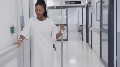 African-american-female-patient-with-drip-walking-in-hospital-corridor,-slow-motion