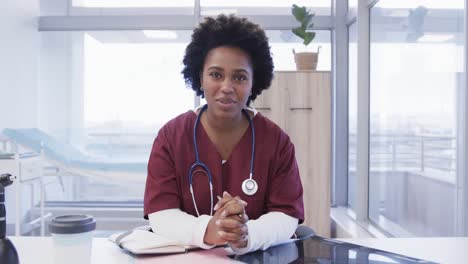 Happy-african-american-female-doctor-making-video-call-in-hospital-office,-slow-motion