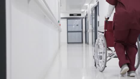 Afroamerikanische-Ärztin-Läuft-Mit-Rollstuhl-Im-Krankenhausflur,-Zeitlupe