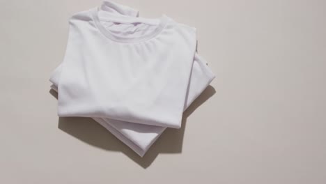 Video-of-stack-of-folded-white-t-shirts-with-copy-space-on-white-background