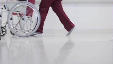 Afroamerikanische-Ärztin-Läuft-Mit-Rollstuhl-Im-Krankenhausflur,-Zeitlupe