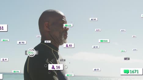 Animation-of-notification-icons-over-african-american-senior-man-walking-at-beach-against-clear-sky