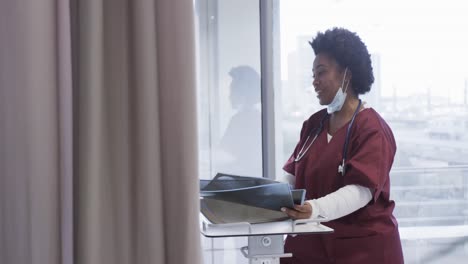 Happy-african-american-female-doctor-discussing-x-ray-images-in-hospital-room,-slow-motion