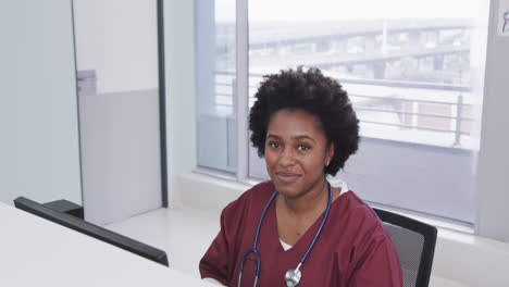 Portrait-of-happy-african-american-female-doctor-using-computer-in-hospital,-slow-motion