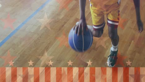 Animation-of-flag-over-low-section-of-african-american-basketball-player-dribbling-ball-in-court
