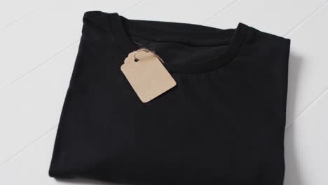 Video-of-flat-lay-of-black-t-shirt-with-tag-and-copy-space-on-white-background