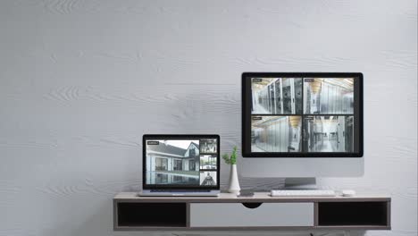 An-Der-Wand-Montierter-Computermonitor-Und-Laptop-Auf-Dem-Schreibtisch-Mit-Überwachungskameraansichten-Auf-Bildschirmen,-Zeitlupe