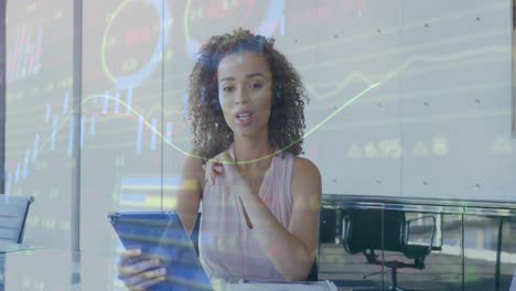 Animation-of-stock-market-data-processing-against-biracial-woman-talking-on-video-call-at-office