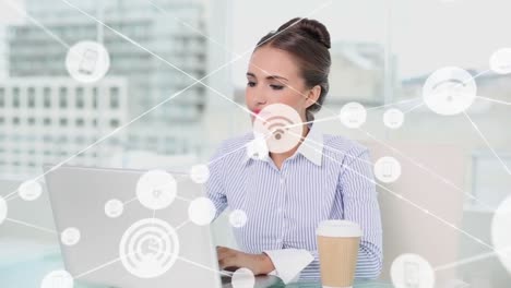 Animation-of-connected-icons-over-beautiful-caucasian-woman-working-on-laptop-in-office